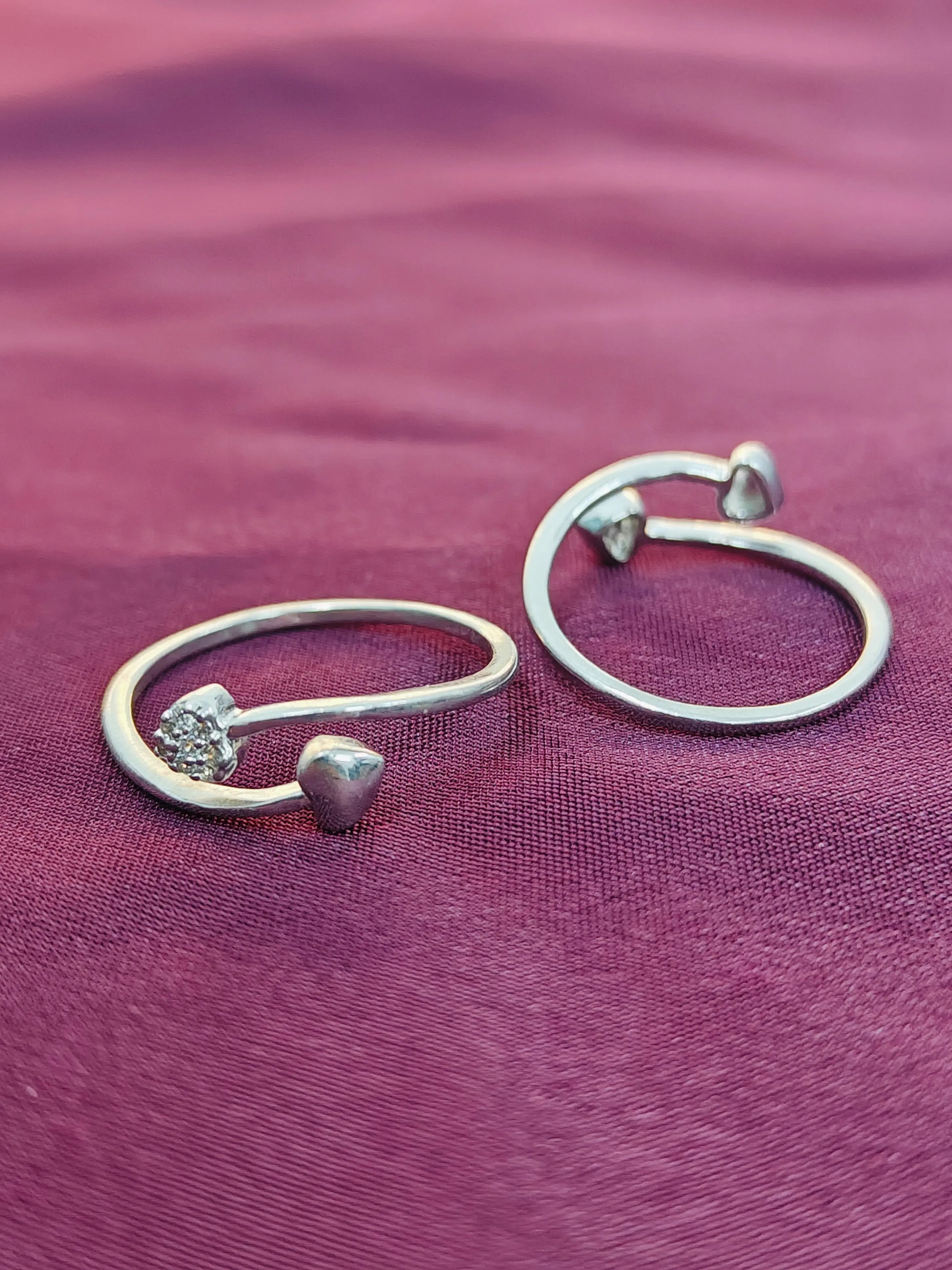 Pair of silver hoop earrings on a purple fabric background